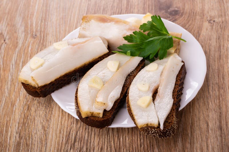 Sandwiches met gezouten varkensvleesreuzel, knoflook, peterselie in plaat op lijst stock foto Sandwiches met gezouten varkensvleesreuzel, knoflook, peterselie in plaat op lijst stock foto