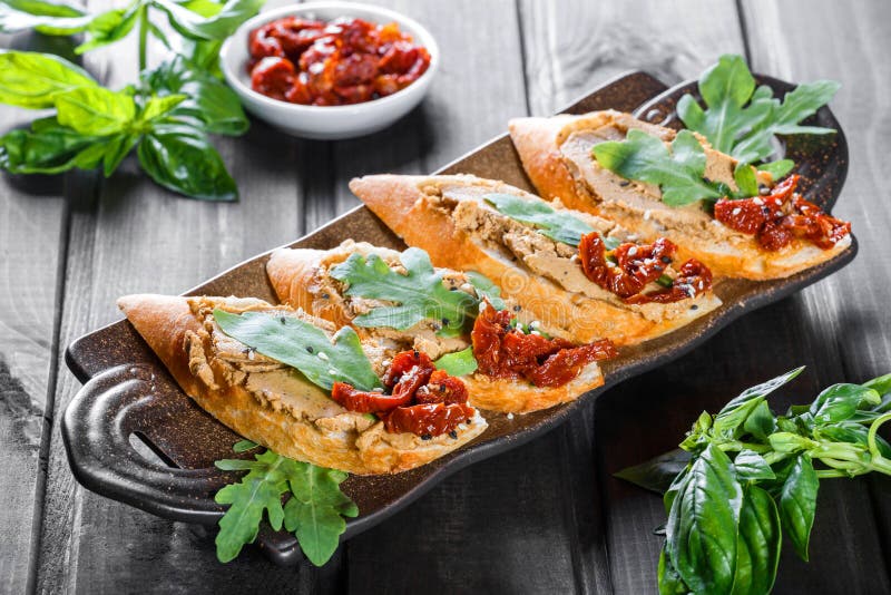Sandwichs italiens - bruschette avec le pâté de viande, l'arugula, la tomate séchée au soleil et les graines sur le pain de ciaba photos stock Sandwichs italiens - bruschette avec le pâté de viande, l'arugula, la tomate séchée au soleil et les graines sur le pain de ciaba photos stock