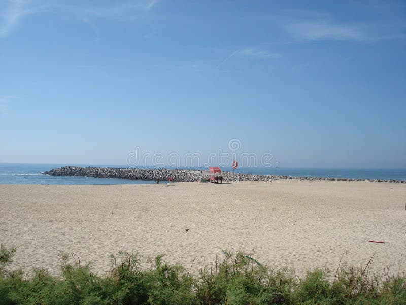 Sandy beach with green plants at the front and an old Baywatch post stock photography Sandy beach with green plants at the front and an old Baywatch post stock photography