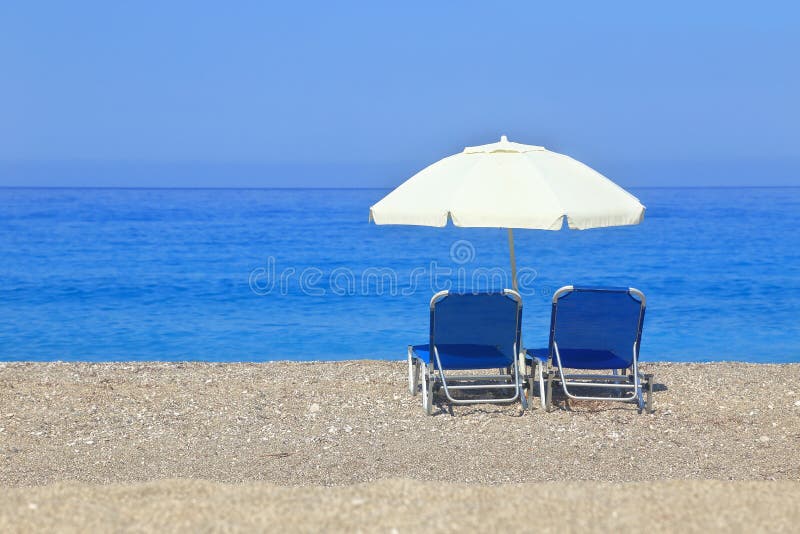 Sandy beach with parasol and two sunbeds royalty free stock photo Sandy beach with parasol and two sunbeds royalty free stock photo