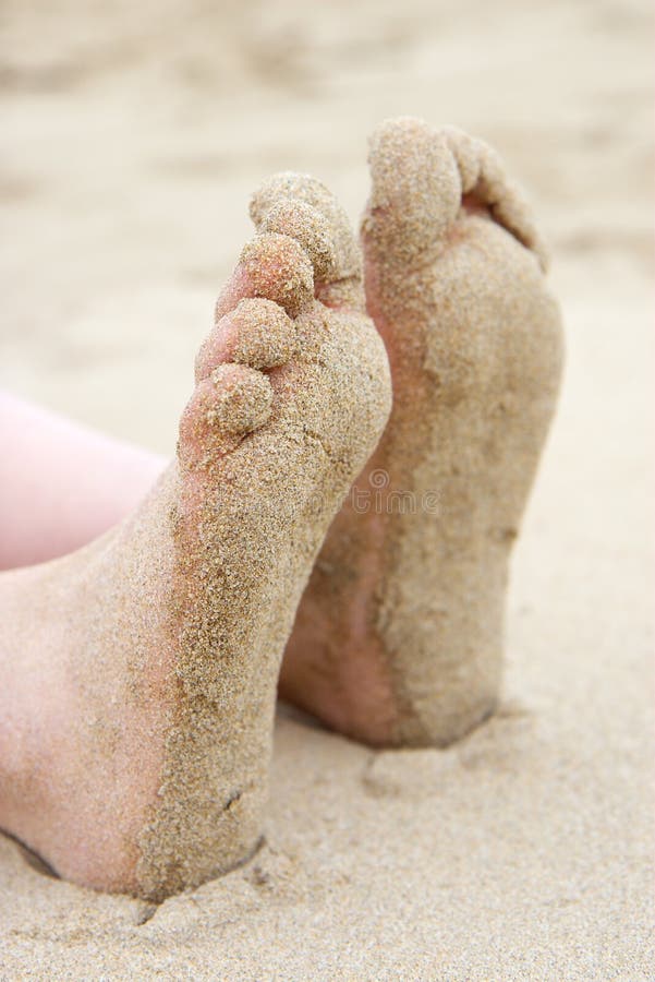 Sand covered feet at the beach. Focus on front foot. Sand covered feet at the beach. Focus on front foot.