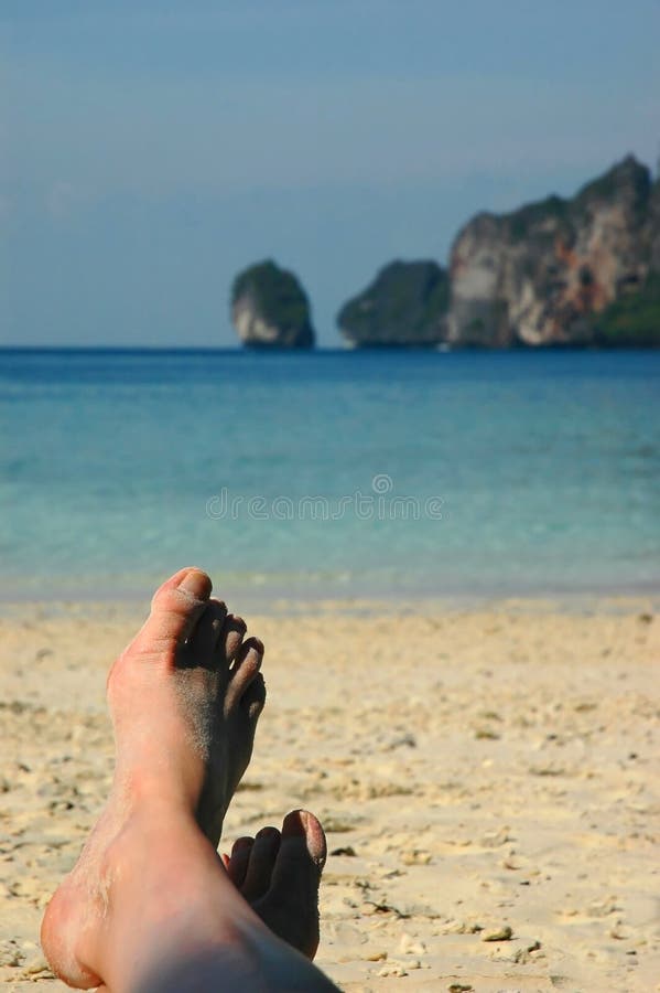 Woman with sandy feet relaxing on a tropical beach in Monkey Beach - Phi Phi Don - Thailand