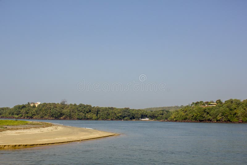 A sandy shore on the background of the river and hills with green trees and houses under a clear blue sky stock images A sandy shore on the background of the river and hills with green trees and houses under a clear blue sky stock images