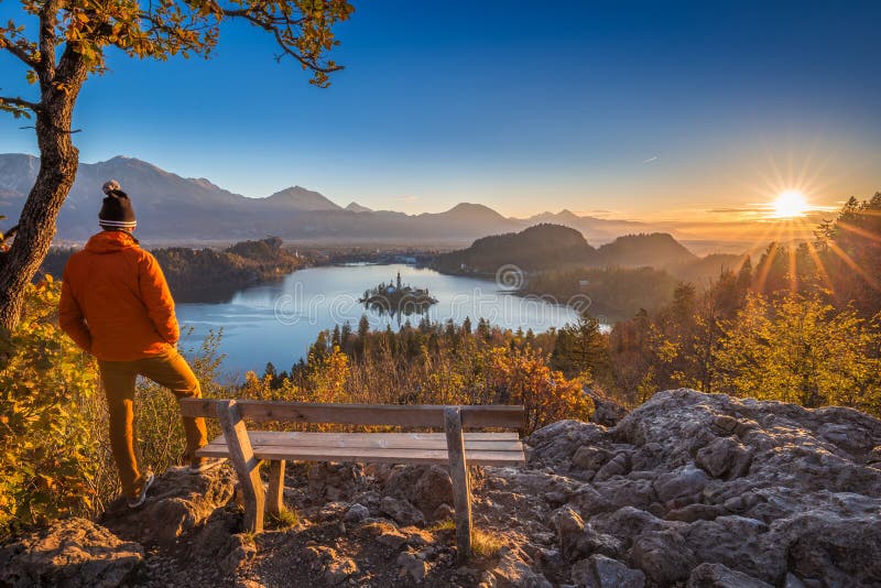 Sangrado, Eslovenia - viajero que lleva la chaqueta anaranjada y el sombrero que disfrutan de la opinión panorámica de la salida foto de archivo Sangrado, Eslovenia - viajero que lleva la chaqueta anaranjada y el sombrero que disfrutan de la opinión panorámica de la salida foto de archivo