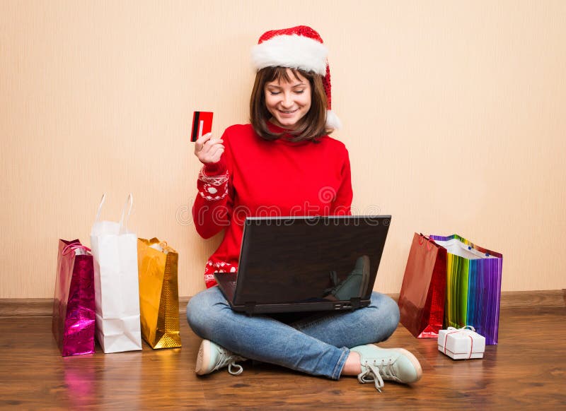 Sankt-Mädchen, das online für das Weihnachten sitzt auf dem Boden mit kauft stockfotografie Sankt-Mädchen, das online für das Weihnachten sitzt auf dem Boden mit kauft stockfotografie