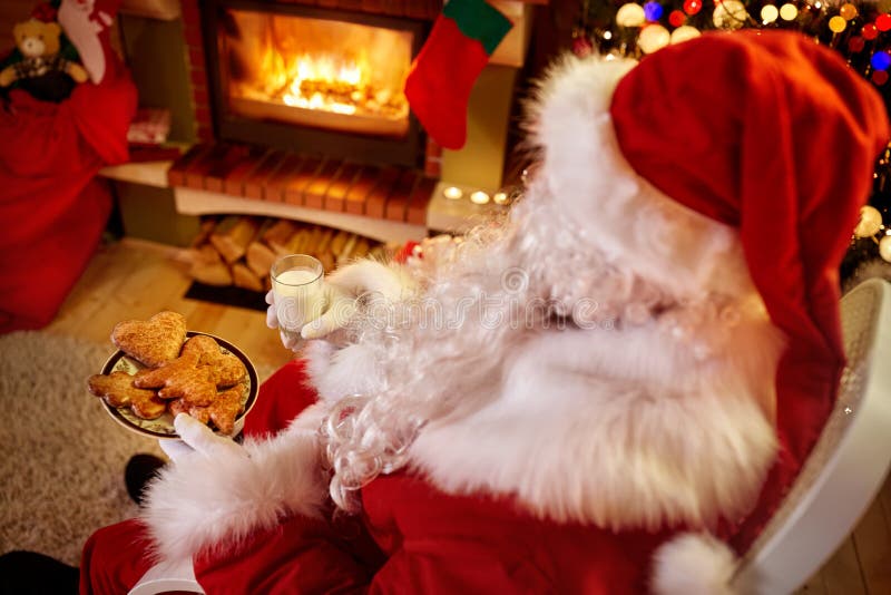 Santa Claus che si rilassa a casa con il latte ed i biscotti freschi immagini stock Santa Claus che si rilassa a casa con il latte ed i biscotti freschi immagini stock