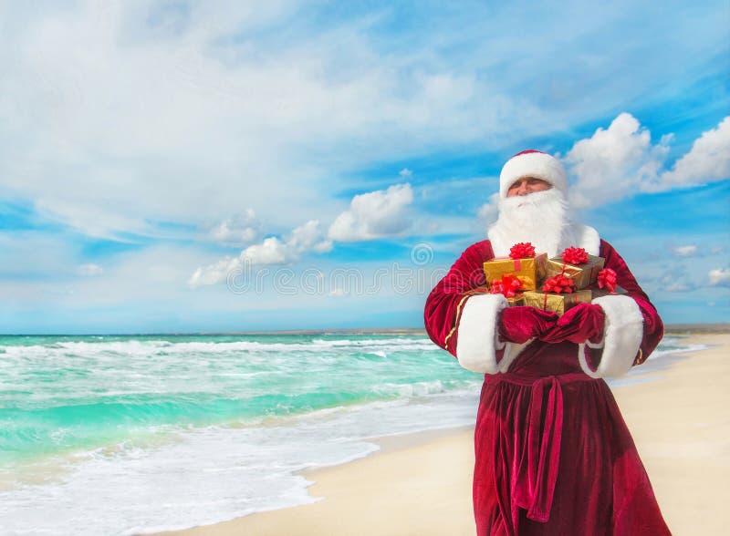 Santa Claus con molti regali dorati sulla spiaggia del mare fotografie stock libere da diritti Santa Claus con molti regali dorati sulla spiaggia del mare fotografie stock libere da diritti