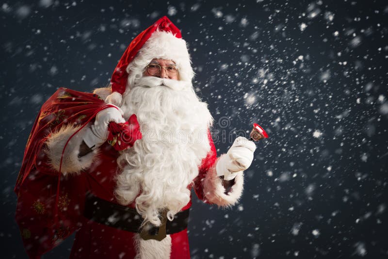 Santa Claus die een zak houden met stelt en een klok op een donkere achtergrond bellen voor stock afbeelding Santa Claus die een zak houden met stelt en een klok op een donkere achtergrond bellen voor stock afbeelding