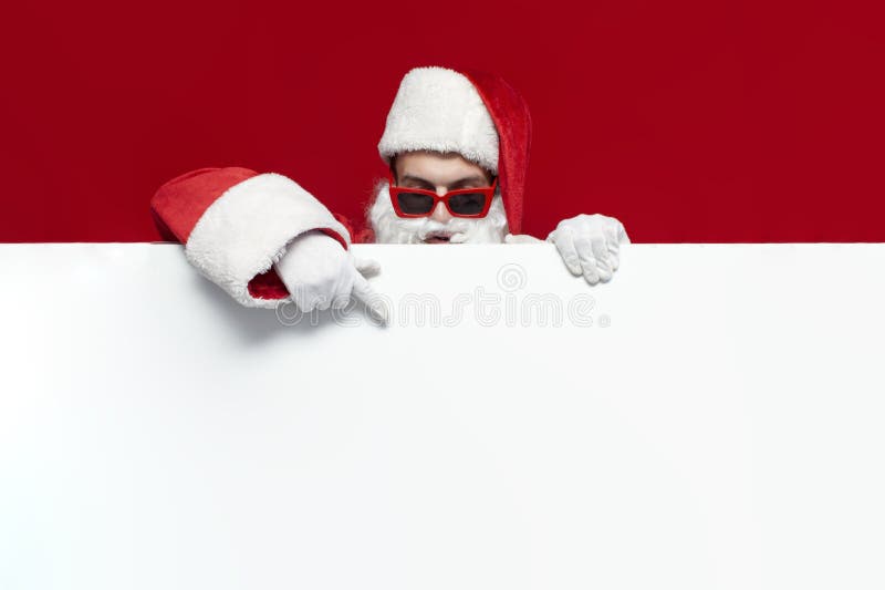 Santa claus en chapeau et lunettes de fête montre bannière vide pour le texte sur fond rouge homme en costume santa photographie stock libre de droits