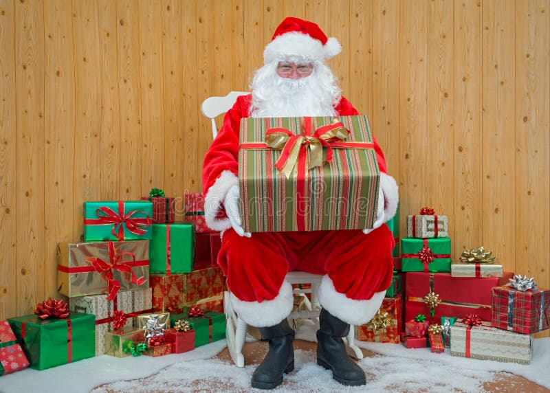 Santa Claus en su gruta que sostenía un regalo envolvió el presente fotografía de archivo Santa Claus en su gruta que sostenía un regalo envolvió el presente fotografía de archivo