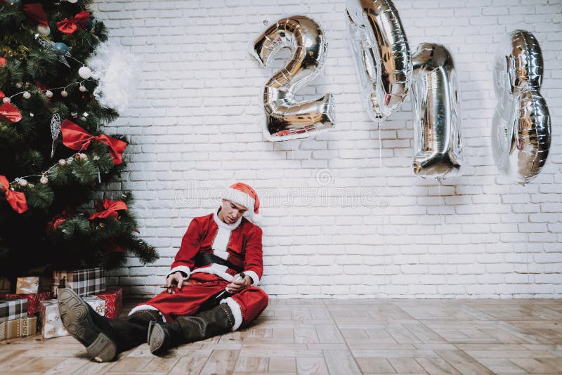 Santa Claus ivre près d'arbre de nouvelle année après partie photo stock Santa Claus ivre près d'arbre de nouvelle année après partie photo stock