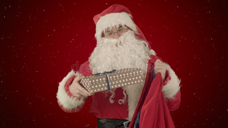 Santa Claus Packaging Gifts på röd bakgrund med snö fotografering för bildbyråer Santa Claus Packaging Gifts på röd bakgrund med snö fotografering för bildbyråer