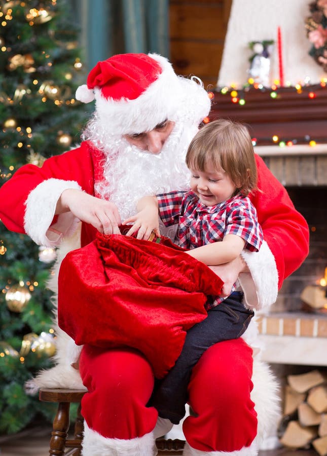 Santa Claus pulls a present out sack to child near royalty free stock photo Santa Claus pulls a present out sack to child near royalty free stock photo