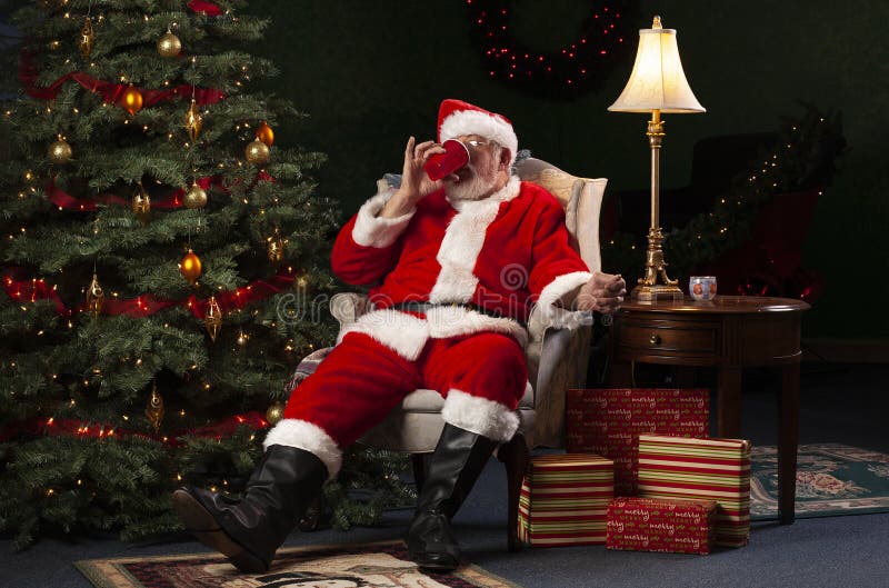 Santa Claus Relaxing in a Chair and Drinking from a Red Cup