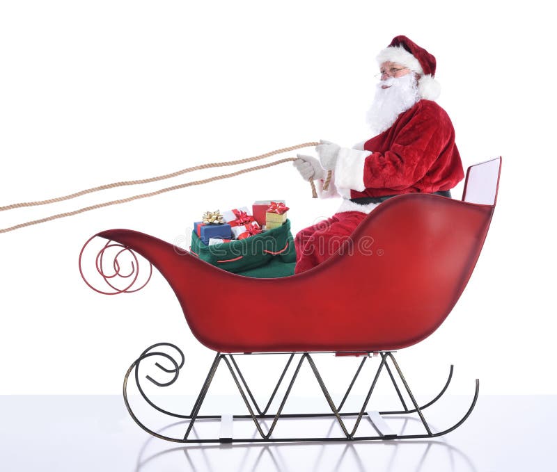Santa Claus sitting in hi sleigh holidng onto the reins, with a sack of presents at his feet. Isolated on white