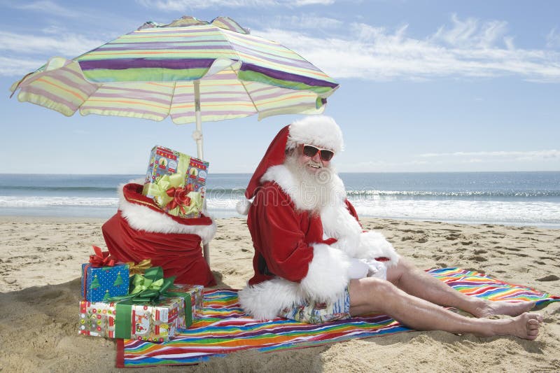 Santa Claus Sitting Under Parasol With gåvor på stranden arkivbilder Santa Claus Sitting Under Parasol With gåvor på stranden arkivbilder