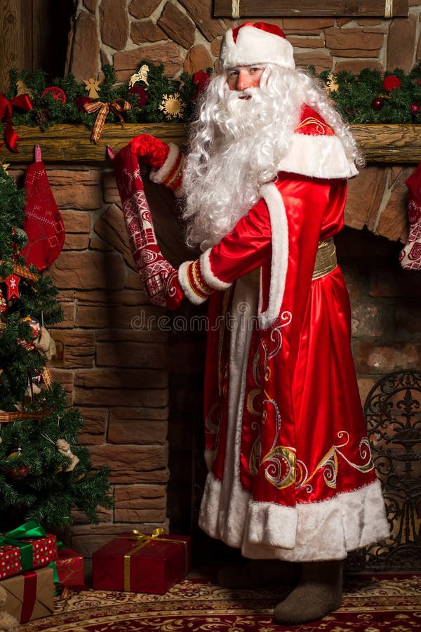 Santa Claus som sätter gåvor i julstrumpor på spisen arkivbilder Santa Claus som sätter gåvor i julstrumpor på spisen arkivbilder