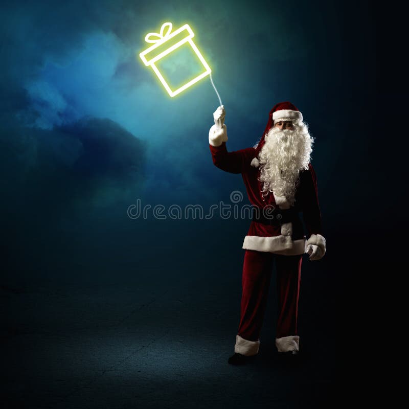 Santa Claus sta tenendo un regalo brillante fotografia stock Santa Claus sta tenendo un regalo brillante fotografia stock