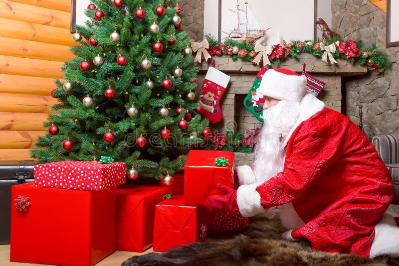 Santa Claus sätter gåvaaskar under julträd royaltyfria foton Santa Claus sätter gåvaaskar under julträd royaltyfria foton