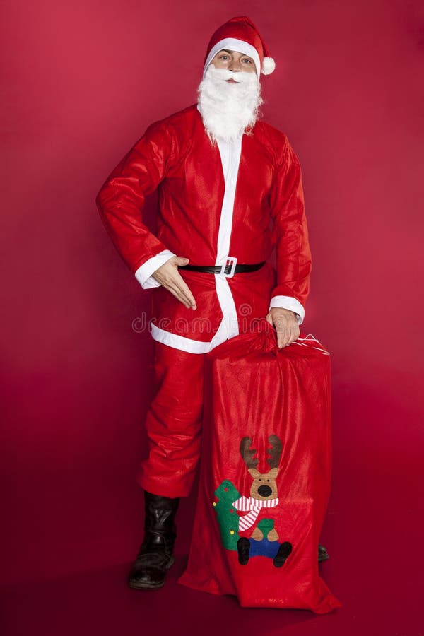 Santa Claus zeigt eine Tasche, die mit Geschenken angefüllt wird lizenzfreies stockbild Santa Claus zeigt eine Tasche, die mit Geschenken angefüllt wird lizenzfreies stockbild