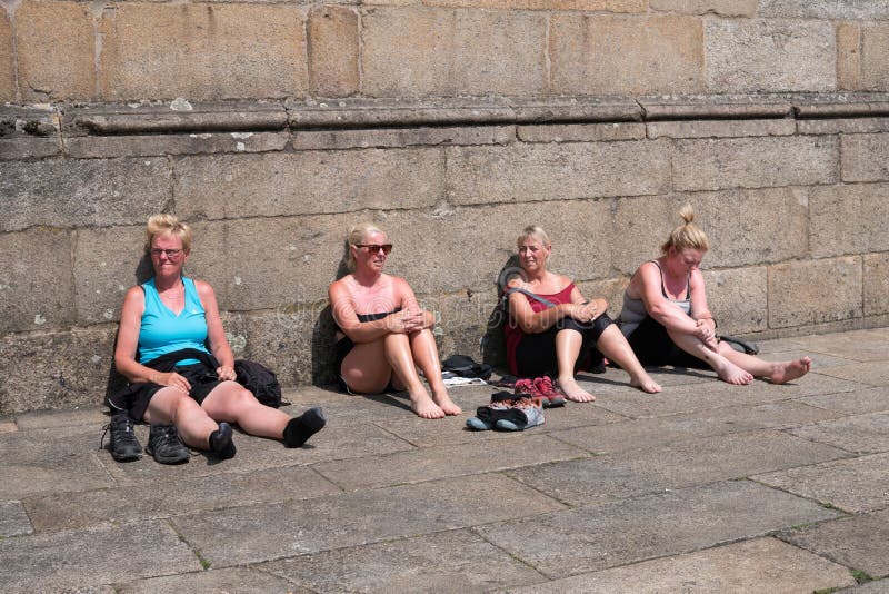 Santiago de Compostela, Spain; july 7, 2019: Group of mature women tourists resting on paving stone with burnt skin. Sun damage