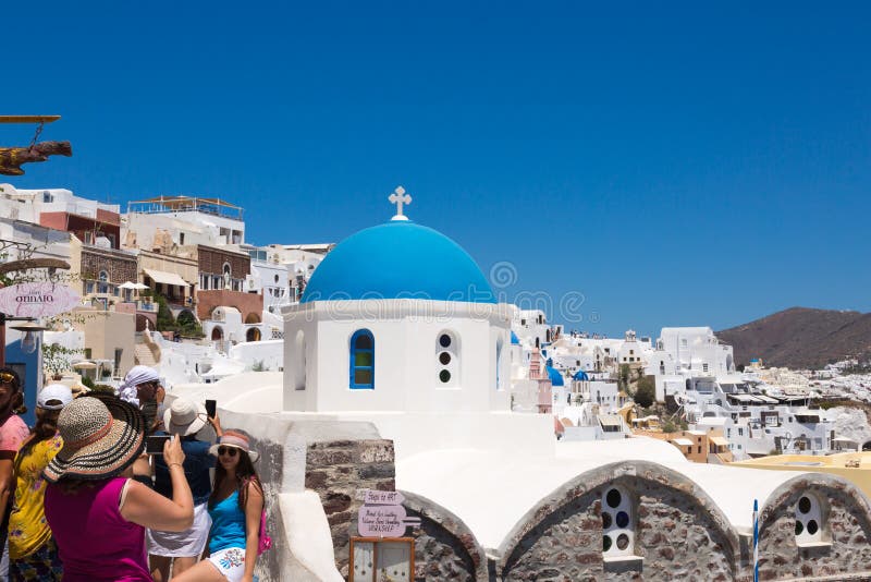 Santorini, Ελλάδα: Οι τουρίστες ανθρώπων κάνουν τις φωτογραφίες στον μπλε θόλο υποβάθρου της εκκλησίας στοκ φωτογραφία με δικαίωμα ελεύθερης χρήσης Santorini, Ελλάδα: Οι τουρίστες ανθρώπων κάνουν τις φωτογραφίες στον μπλε θόλο υποβάθρου της εκκλησίας στοκ φωτογραφία με δικαίωμα ελεύθερης χρήσης