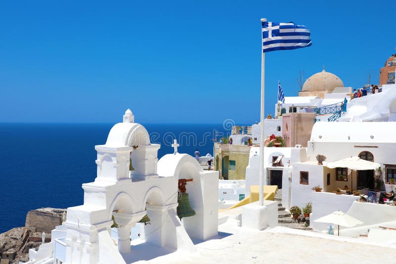 SANTORINI, ΕΛΛΑΔΑ - 20 ΙΟΥΛΊΟΥ 2018: όμορφη άποψη Oia του χωριού με την ελληνική σημαία σε Santorini, Ελλάδα στοκ εικόνες SANTORINI, ΕΛΛΑΔΑ - 20 ΙΟΥΛΊΟΥ 2018: όμορφη άποψη Oia του χωριού με την ελληνική σημαία σε Santorini, Ελλάδα στοκ εικόνες
