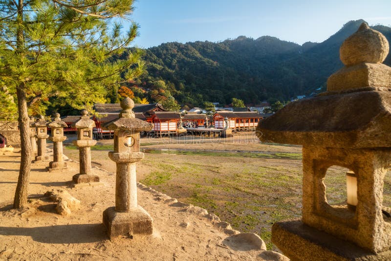 Santuario di Itsukushima con le lanterne di pietra nella priorità alta sull'isola di Miyajima nel Giappone fotografie stock Santuario di Itsukushima con le lanterne di pietra nella priorità alta sull'isola di Miyajima nel Giappone fotografie stock