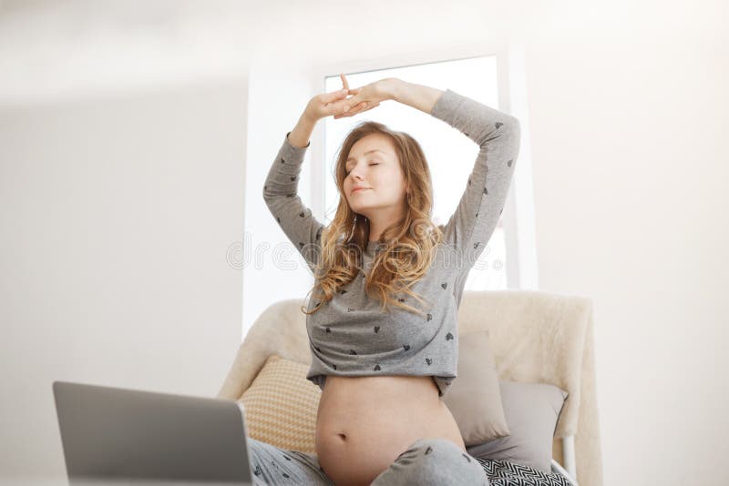 Santé et beauté Concept de maternité Belle jeune femme enceinte décontractée avec les cheveux bouclés blonds dans la maison grise photos libres de droits Santé et beauté Concept de maternité Belle jeune femme enceinte décontractée avec les cheveux bouclés blonds dans la maison grise photos libres de droits
