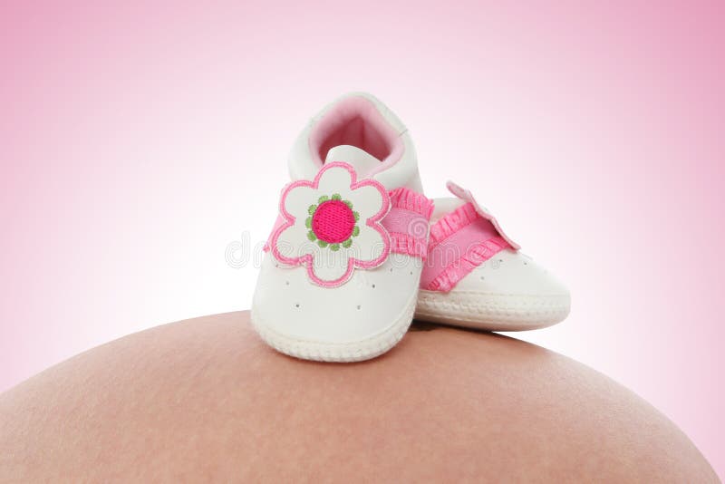 Sapatas de bebê na mulher gravida imagem de stock Sapatas de bebê na mulher gravida imagem de stock