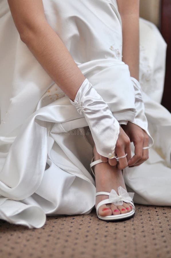 Bride putting on wedding shoes. Bride putting on wedding shoes