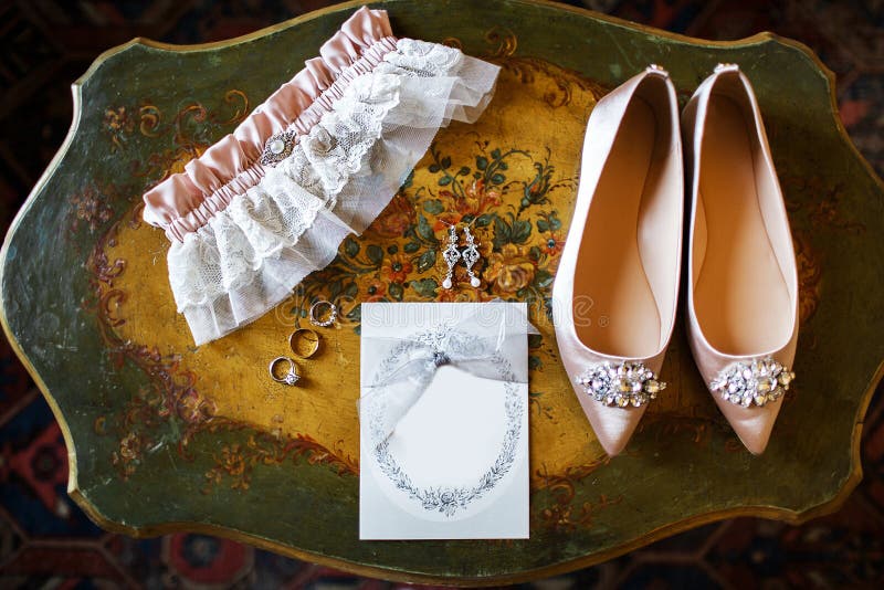 Sapatas do casamento na tabela do vintage, na liga nupcial e nos anéis imagem de stock Sapatas do casamento na tabela do vintage, na liga nupcial e nos anéis imagem de stock