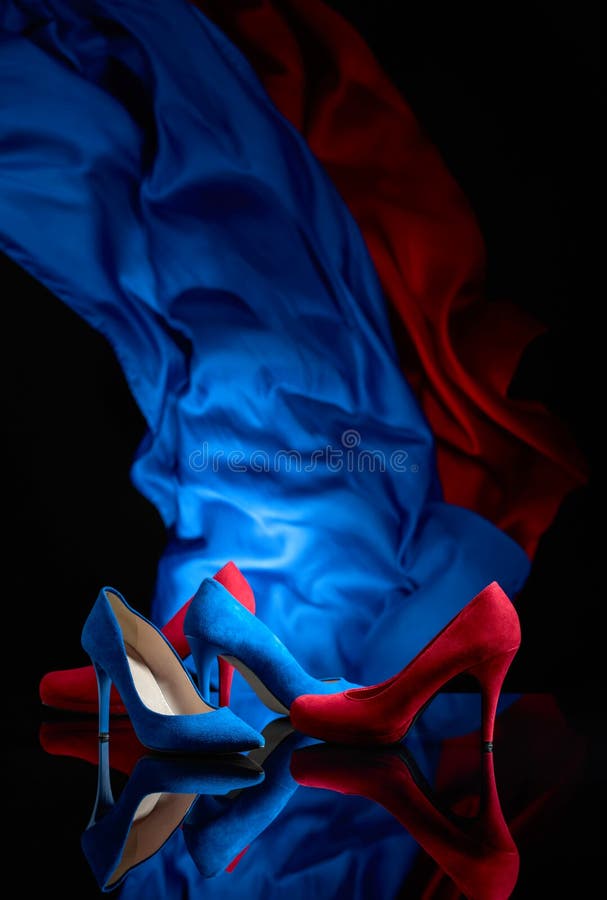Sapatas do veludo de algod?o das mulheres azuis e vermelhas em um fundo reflexivo preto fotografia de stock Sapatas do veludo de algod?o das mulheres azuis e vermelhas em um fundo reflexivo preto fotografia de stock