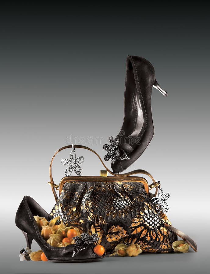 A still life arrangement of a pair of woman's black high heel shoes and purse with matching decorations. A still life arrangement of a pair of woman's black high heel shoes and purse with matching decorations.