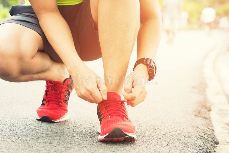 Sapatas Running Os t?nis de corrida descal?os fecham-se acima atleta masculino que senta-se amarrando laços para movimentar-se imagem de stock royalty free Sapatas Running Os t?nis de corrida descal?os fecham-se acima atleta masculino que senta-se amarrando laços para movimentar-se imagem de stock royalty free