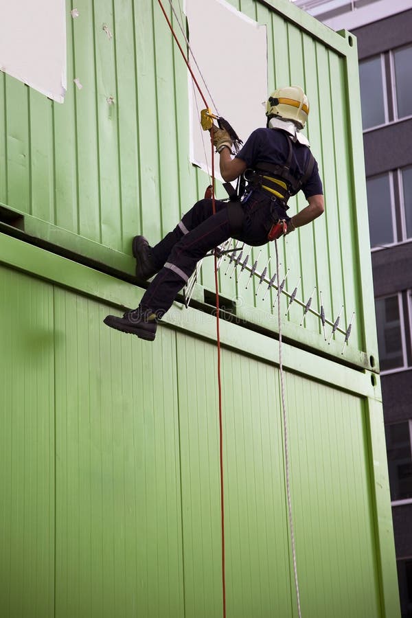 Fireman abseiling on the side of green containers during a drill. Fireman abseiling on the side of green containers during a drill.