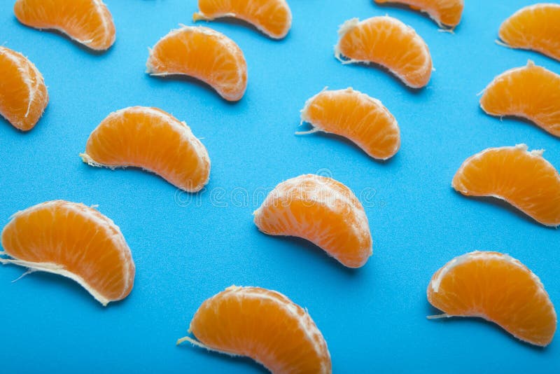 Sappige organische plakken en stukken van mandarin zonder schil op een blauwe achtergrond stock afbeelding Sappige organische plakken en stukken van mandarin zonder schil op een blauwe achtergrond stock afbeelding