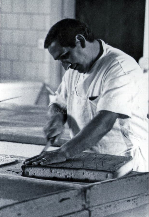 SARDEGNA, ITALY, 1970 - Pastry chef carefully cuts a sponge cake prepared in his workshop stock photos SARDEGNA, ITALY, 1970 - Pastry chef carefully cuts a sponge cake prepared in his workshop stock photos