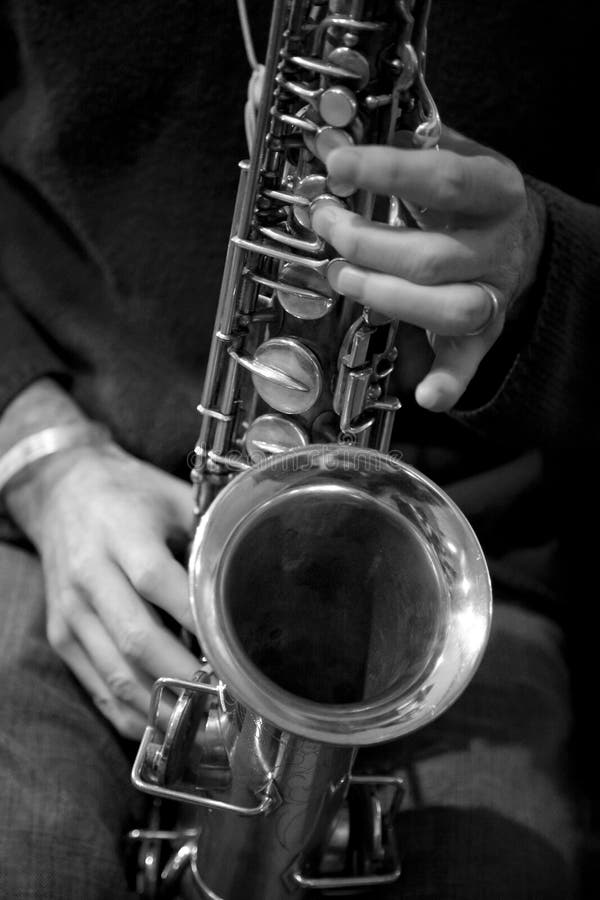 Close up black and white image of a saxaphone being played. Close up black and white image of a saxaphone being played.