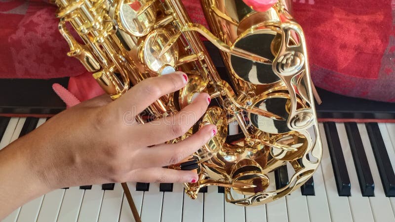 Sassofono, mano della ragazza ed il piano immagine stock Sassofono, mano della ragazza ed il piano immagine stock