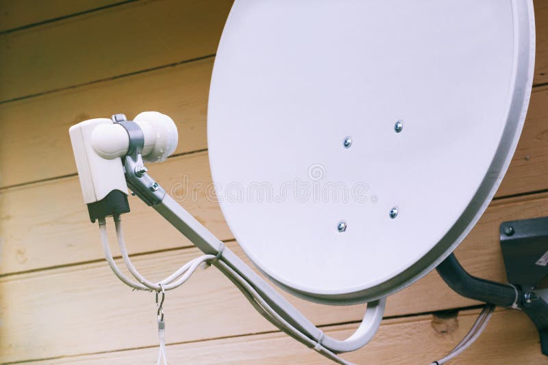 Satellit- maträtt på väggen av ett landshus arkivbild Satellit- maträtt på väggen av ett landshus arkivbild
