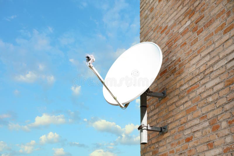Satellite Dish on Brick Wall of Building Against Blue Sky Stock Image