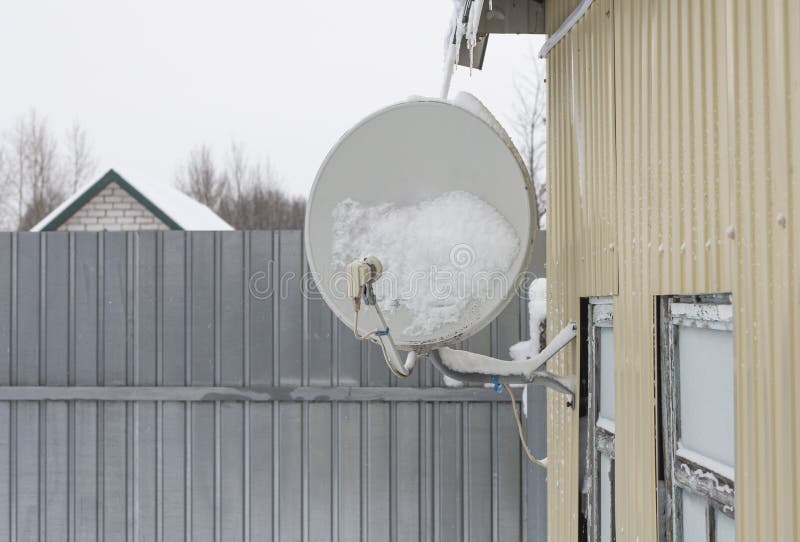 Satellite Dish Fixed To the Wall of a House in the Snow after a