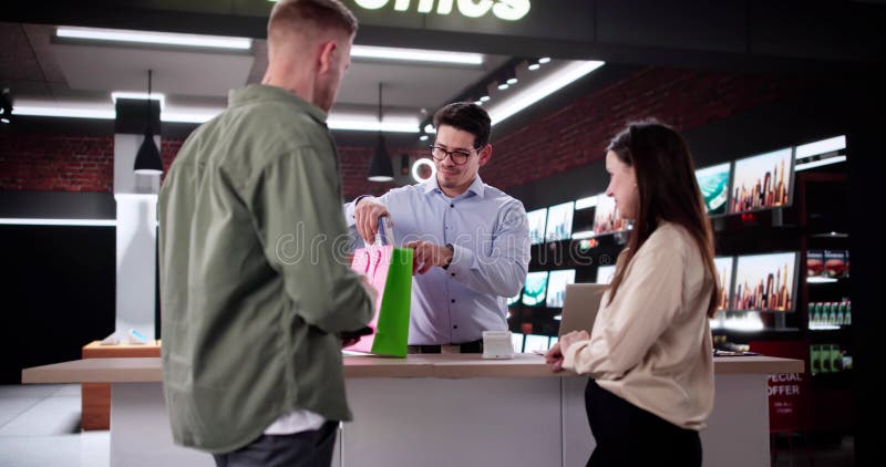 Satisfied Couple At Electronic Store Checkout, Paying With Credit Card royalty free stock photo