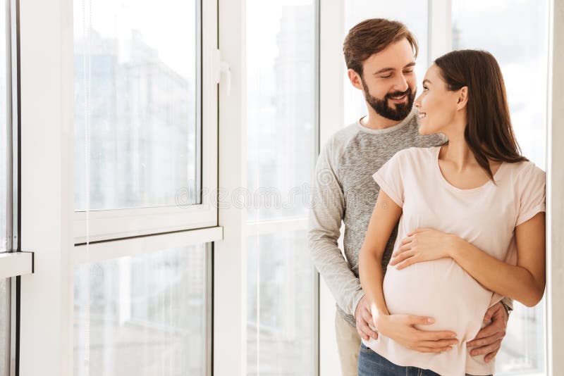 Satisfied pregnant young couple hugging royalty free stock photography