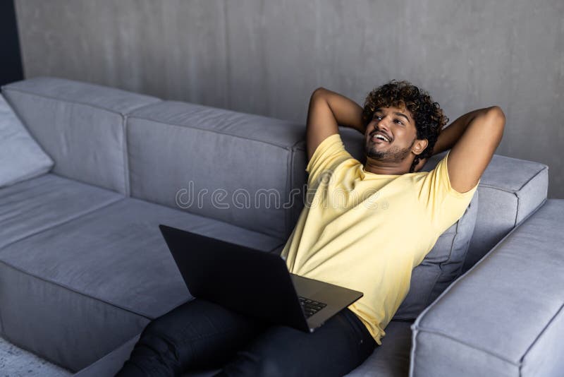 Satisfied Relaxed Young Indian Man Chilling On Sofa In Living Room