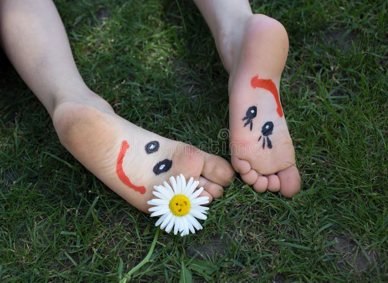 Satisfied smiles are drawn on the two left children`s bare feet, the children lie on the grass