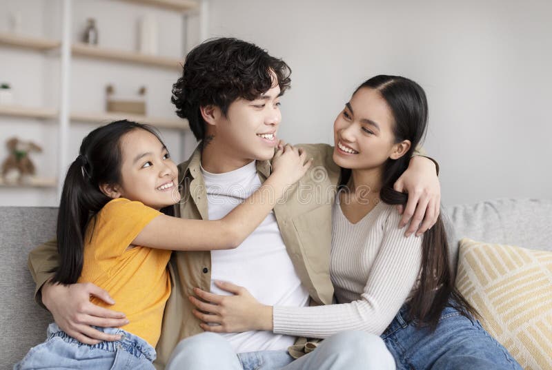 Satisfied young korean family hugging and enjoying rest, free time on weekend