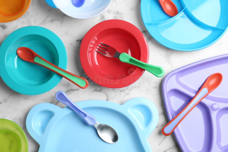 Satz des bunten Plastikdishware auf flacher Lage der Marmortabelle. einsatzbereit Babynahrung