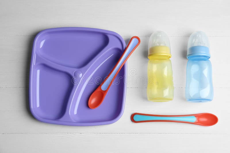 Satz des bunten Plastikdishware auf flacher Lage des Holztischs. einsatzbereit Babynahrung